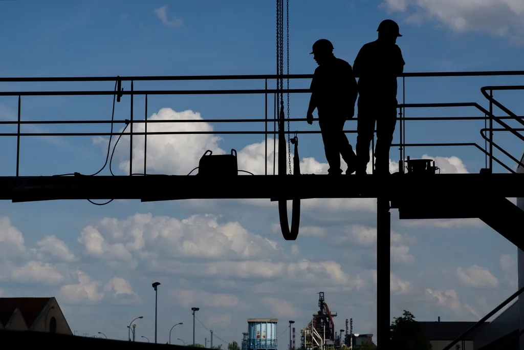 Operarios sobre estructura elevada trabajando en altura a contraluz